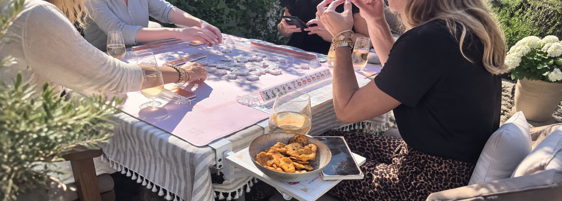 Women enjoying American Mah-Jongg and drinks at a relaxed outdoor gathering